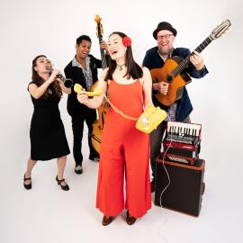 four individuals on a white background, on female is singing, the other three band members are holding instruments